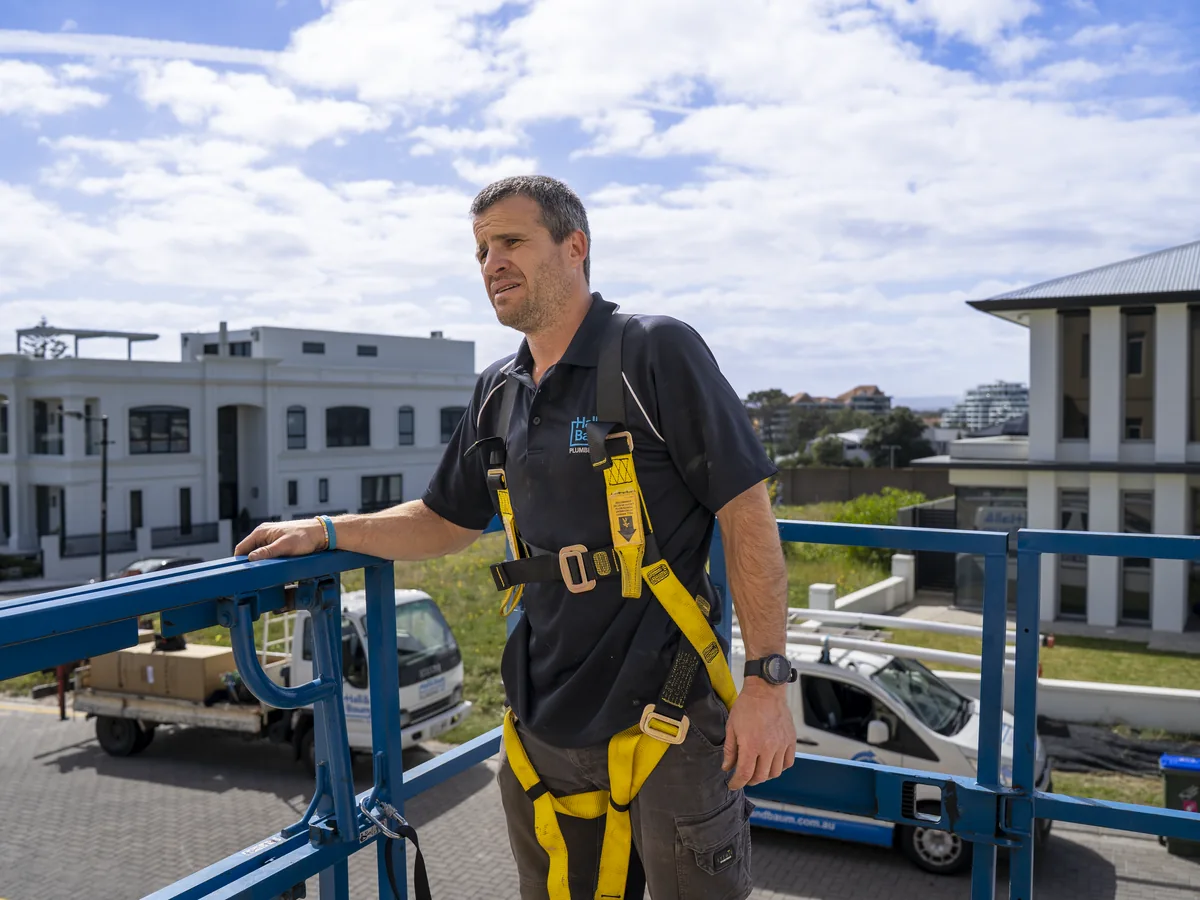 Hall & Baum plumber wearing a safety harness in an elevated work platform